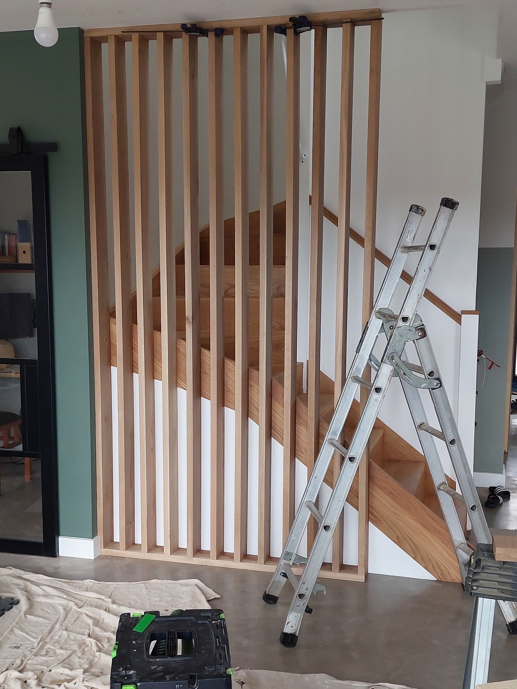 Wooden staircase with a metal ladder against a wall